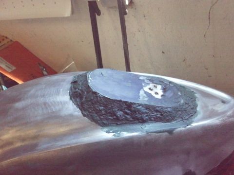1995 Ford F-150 - A section of a vehicle's body panel is undergoing repair work, showing filler and primer application.