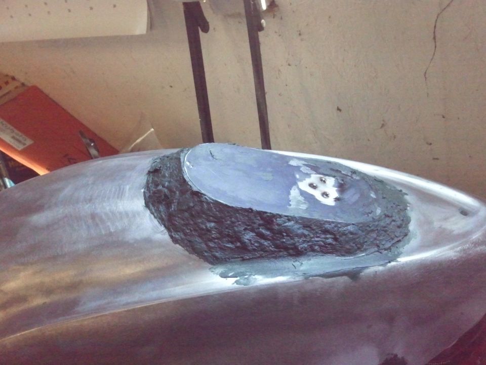 Close-up of a vehicle's metal body panel being repaired with filler and primer