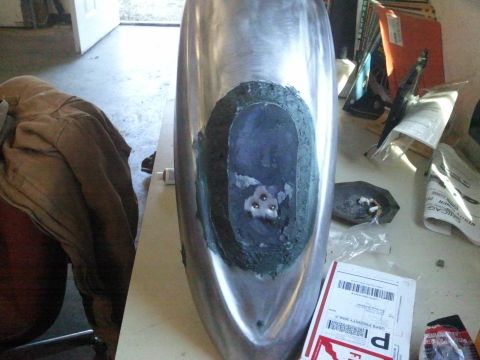 1995 Ford F-150 - A metal fender with a hole cut out, possibly for a custom modification or repair, sits on a workbench.