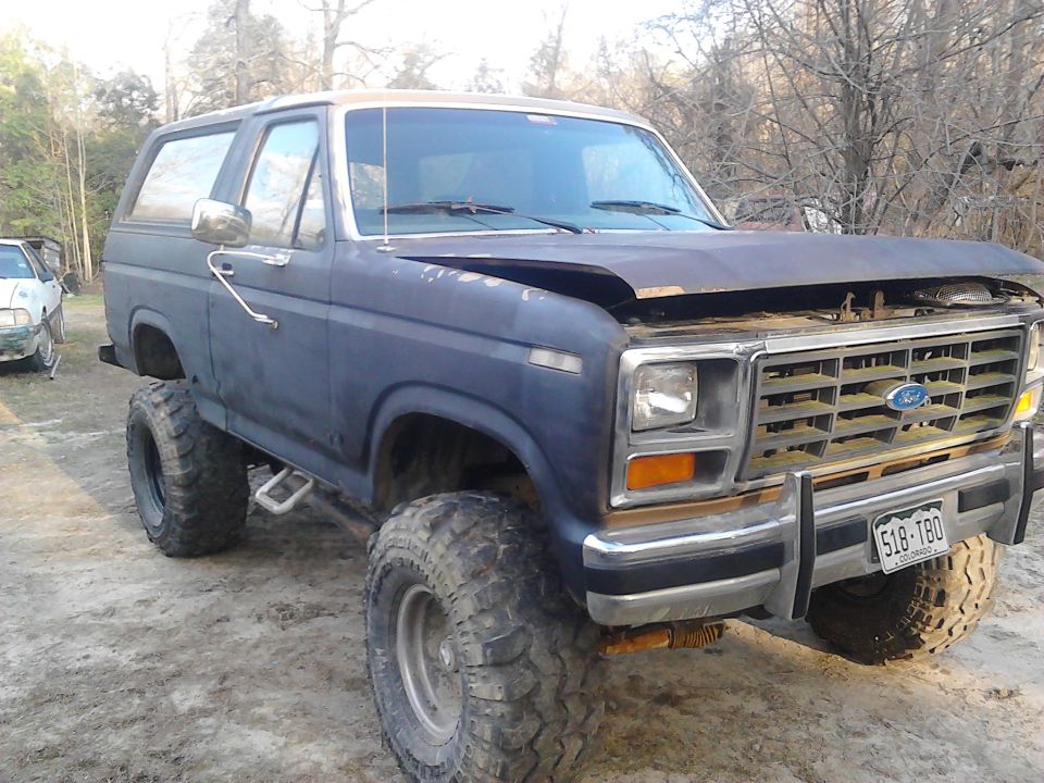 Blue lifted Ford Bronco with aftermarket wheels and tires, hood open