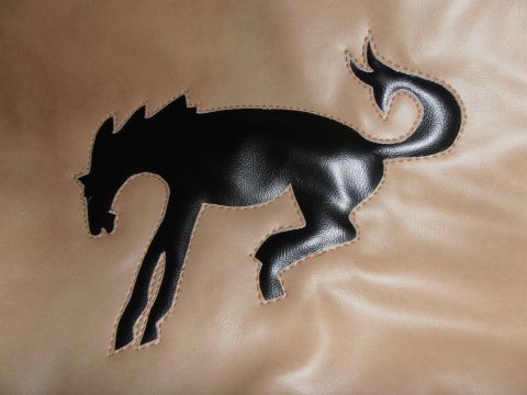 1990 Ford Bronco - This image shows a black bronco emblem stitched onto a tan material, likely a tire cover or seat cover.