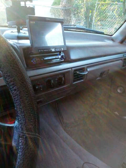 1995 Ford Bronco - The interior of a vehicle features an aftermarket screen and radio unit, with a view of the dashboard and floor mats.