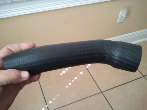 1994 Ford Bronco - A black rubber hose, likely for a vehicle's cooling system, is held by a person's hand.