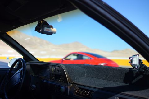1995 Ford Taurus - View from inside a car, looking out at a red sports car on a track with mountains in the distance.