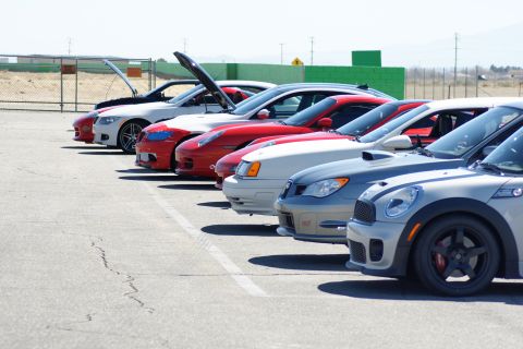 1995 Ford Taurus - Several cars are parked in a row on a sunny day, with some of their hoods raised.