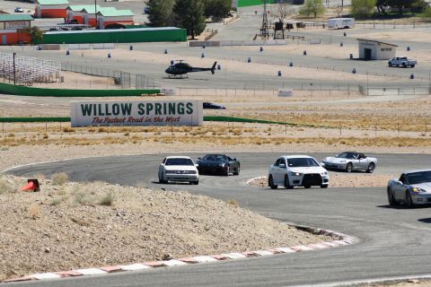1995 Ford Taurus - Several cars are on a race track, with a helicopter and buildings visible in the distance.
