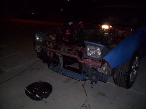 1995 Ford Probe - The front of a car is disassembled at night, with tools and a drain pan nearby.