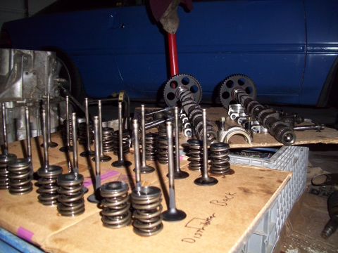 1995 Ford Probe - Engine components are organized on a surface, with a blue vehicle partially visible behind them.