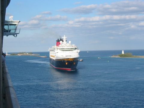 1992 Ford Bronco - A large cruise ship navigates the blue ocean waters, passing a small island topped with a lighthouse under a partly cloudy sky.
