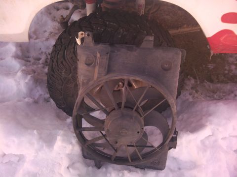 1979 Ford Bronco - An electric fan assembly is positioned in front of a vehicle's tire, surrounded by snow.