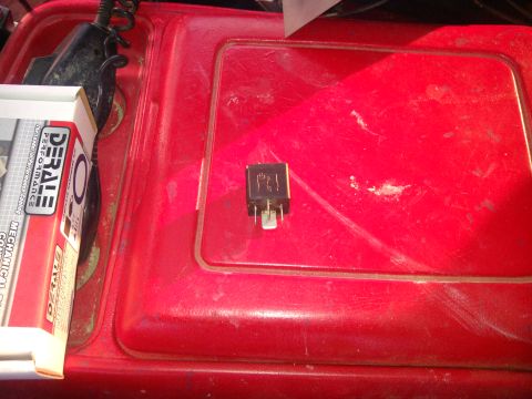 1979 Ford Bronco - A close-up shows an automotive relay and a box of performance parts on a red surface.