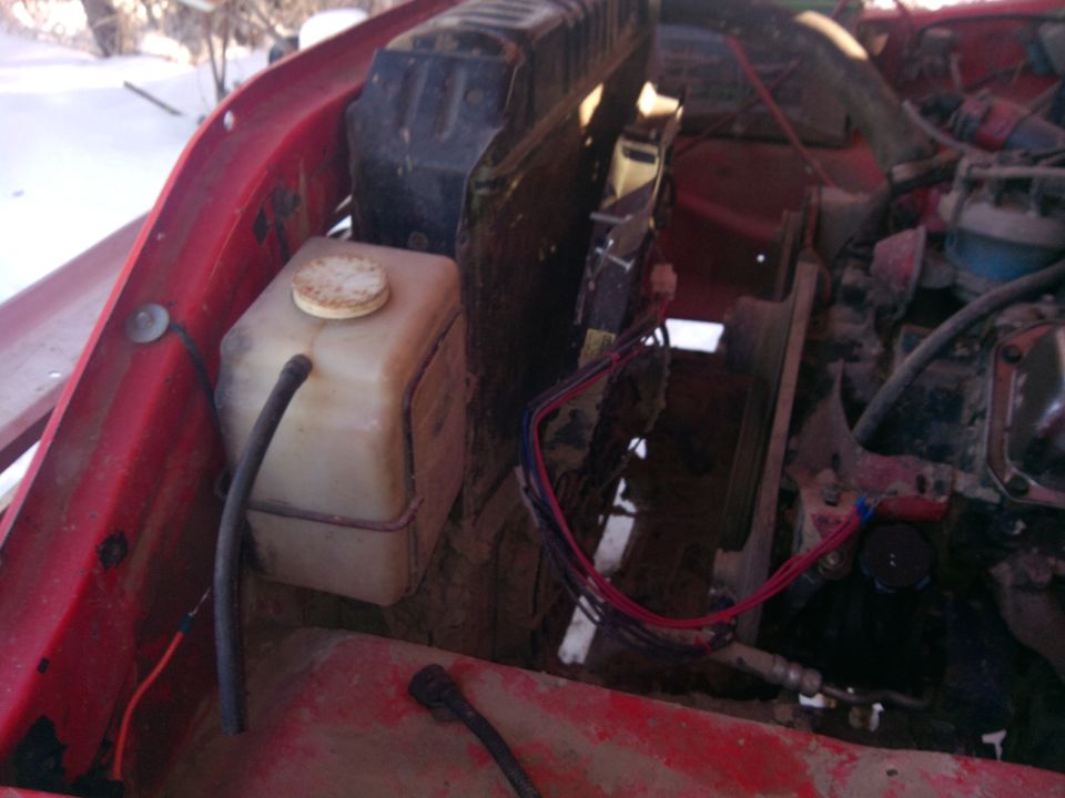 Engine bay with coolant reservoir and fan