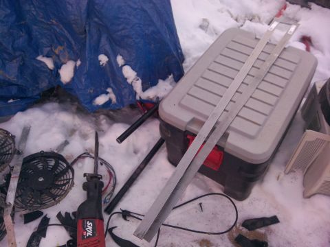 1979 Ford Bronco - An electric fan and a SKIL reciprocating saw are visible among tools and debris in the snow.