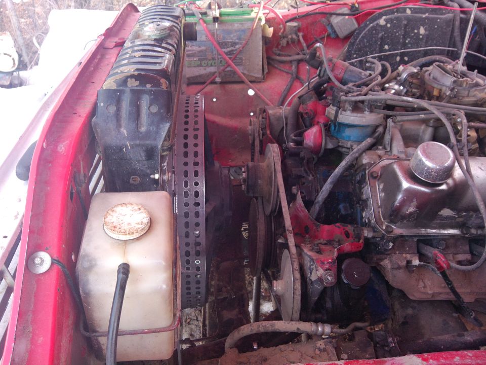 Engine bay with radiator, battery, belts, and engine components visible