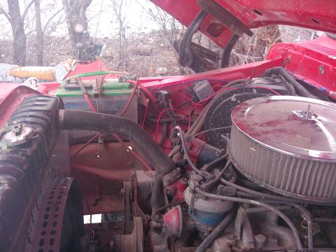 1979 Ford Bronco - The engine bay of a vehicle is shown with the hood open, revealing various mechanical parts and two batteries.