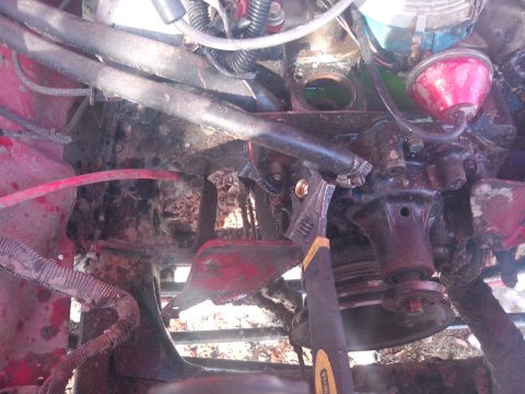 1979 Ford Bronco - An adjustable wrench is used on a hose clamp in a cluttered engine bay. The registry claims this is a 1979 Ford Bronco, but the image does…