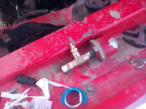 1979 Ford Bronco - A pressure gauge and various tools are laid out on the red surface of a vehicle's engine bay.