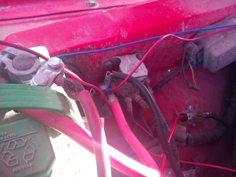 1979 Ford Bronco - Wiring and battery terminals visible in a red engine bay, with recycling symbols on the battery.