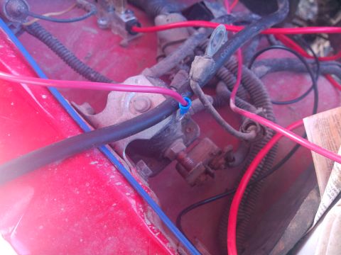 1979 Ford Bronco - Close-up view of the engine bay wiring harness and electrical components in a red vehicle.