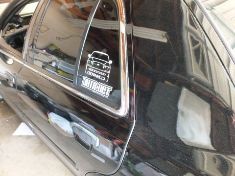 2003 Ford Crown Victoria - White CrownVic.ca and ADTR.net window decals seen on the small rear quarter glass of a black sedan in a garage
