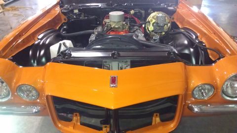 1973 Chevrolet Camaro - The front view of an orange Chevrolet Camaro reveals its engine bay and V8 engine.