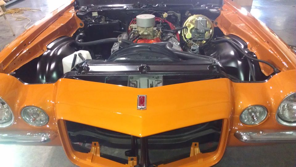 Orange 1970 Chevrolet Camaro engine bay with hood open, showing V8 engine and front grille