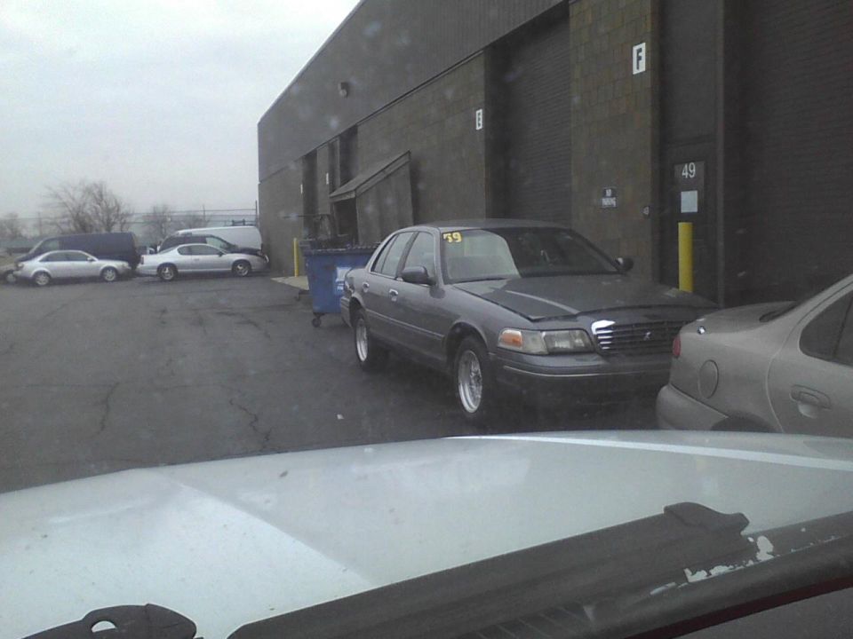 Gray 2003 Ford Crown Victoria with yellow 59 tag on windshield, parked outside