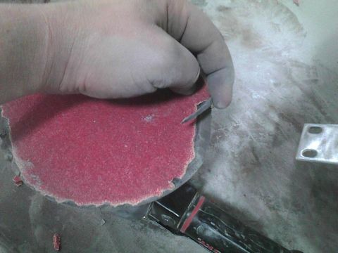 2003 Ford Crown Victoria - A hand is shown sanding a surface with a red abrasive disc, revealing a metal component underneath.