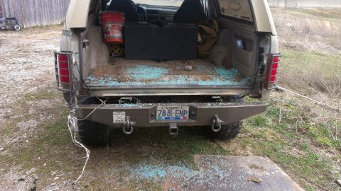 1995 Ford Bronco - The rear of a tan 1992 Ford Bronco shows shattered glass and a custom bumper.