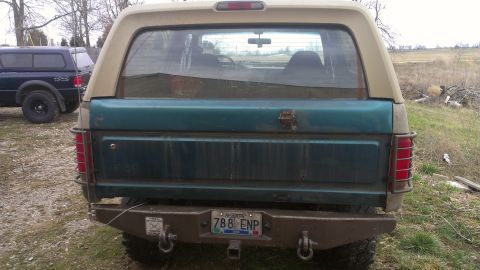 1995 Ford Bronco - This teal and tan SUV is seen from the rear, a custom bumper and a visible license plate.