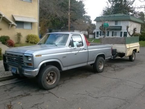 1991 Ford Bronco - This silver pickup truck appears to be from the early 1980s, towing a trailer.