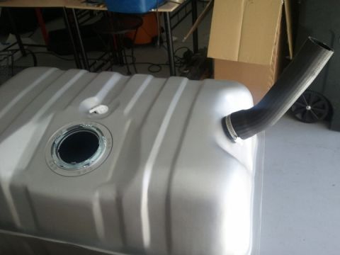 1994 Ford Bronco - A silver-colored fuel tank with a ribbed surface and a black hose attached to its filler neck.