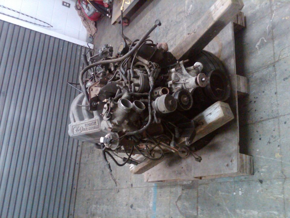 Engine assembly with intake manifold and wiring harness, resting on wooden supports