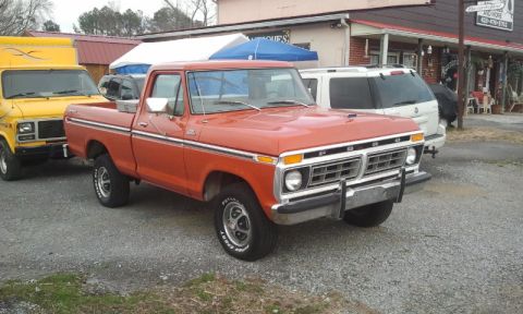 1987 Ford Bronco - A vintage Ford pickup truck is parked outside a building with other vehicles.