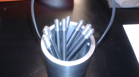 1996 Ford Bronco - A collection of threaded metal rods are held upright in a cylindrical container.