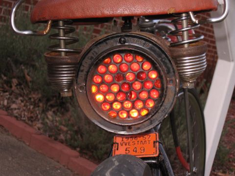 1994 Ford Bronco - A close-up of a vintage bicycle's tail light assembly, a license plate from 1956-57.
