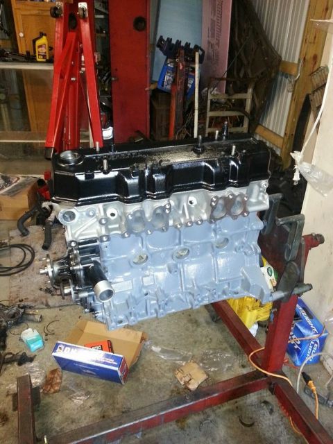 1987 Toyota 4Runner - Engine block on a stand in a garage, surrounded by tools and parts.