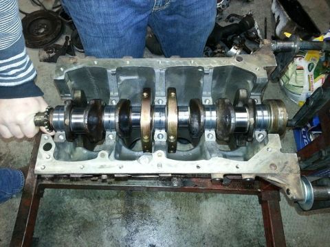 1987 Toyota 4Runner - A person's hands are shown working on an engine block with a visible crankshaft and connecting rods.