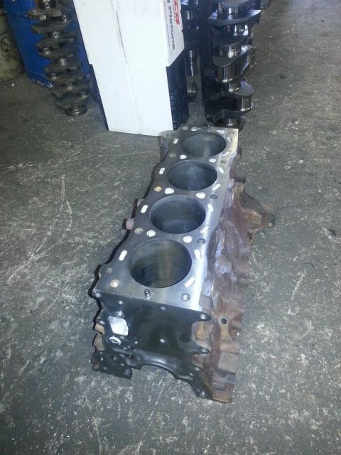 1987 Toyota 4Runner - A bare engine block rests on a workshop floor, with spare crankshafts nearby.