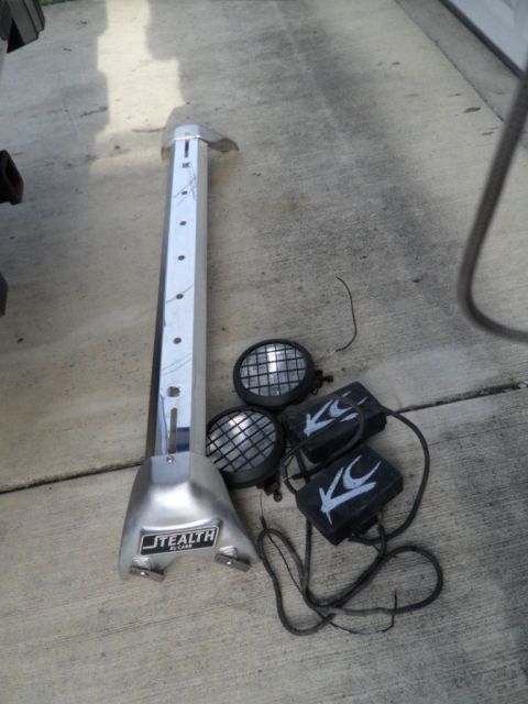 1994 Jeep Cherokee - Off-road lighting components, including a light bar and two KC lights, are laid out on a concrete surface.