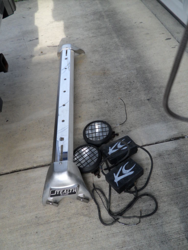 Silver light bar with "STEALTH" logo and two KC lights with black housings and wire harnesses on concrete