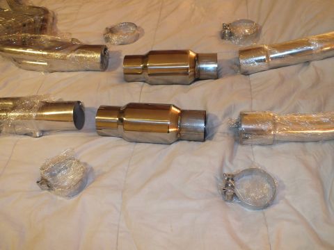 2003 Ford Crown Victoria - Pair of polished catalytic converter canisters and wrapped pipe sections with V-band clamps laid out on a bed