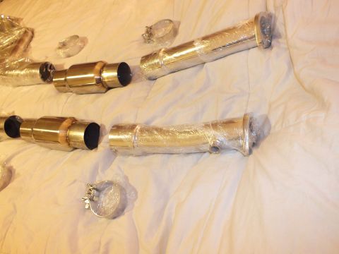 2003 Ford Crown Victoria - Plastic-wrapped polished exhaust pipe sections with capped catalytic converters and clamps arranged on a bed