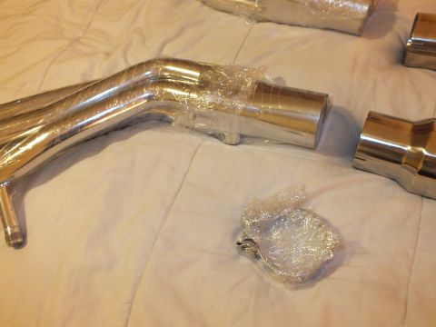 2003 Ford Crown Victoria - Bent stainless exhaust piping with slip joints and a wrapped clamp resting on a bed