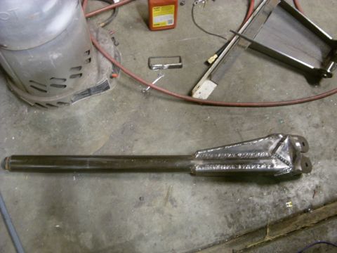 1967 Ford F-250 - A fabricated metal part, possibly for a vehicle suspension or drivetrain, lies on a workshop floor.
