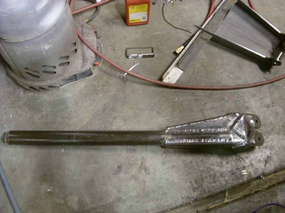 Welded metal component with a long cylindrical shaft and a triangular bracket at one end