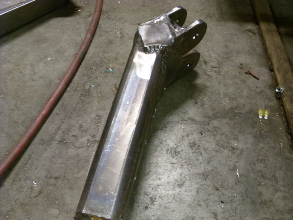 Welded metal component with two prongs at one end, resting on a concrete floor