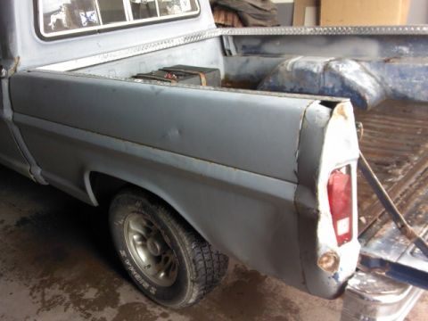 1967 Ford F-100 - Rear view of a 1967 Ford F-100 pickup truck bed, primer finish, some body damage visible.