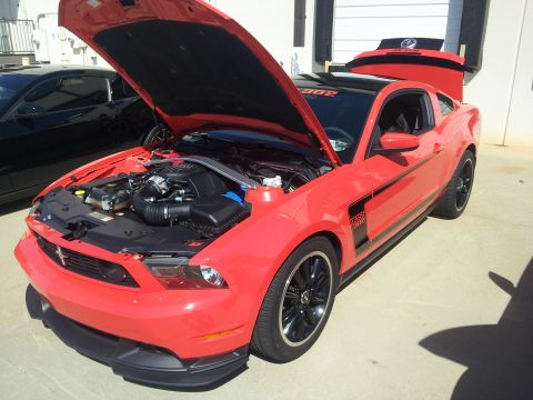 1965 Ford Mustang - Red 2012 Ford Mustang Boss 302 with hood and trunk open, parked outdoors. Another car is visible behind it.