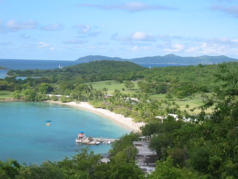 1992 Ford Bronco - A scenic view of a tropical bay with a dock and boats, overlooking lush green hills and the ocean.